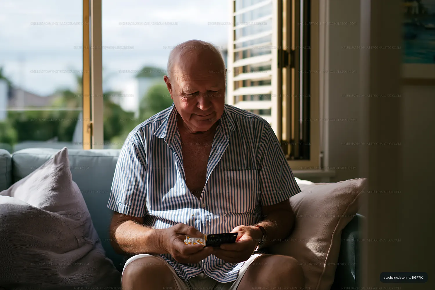 Older man using smartphone while sitting on couch in living room