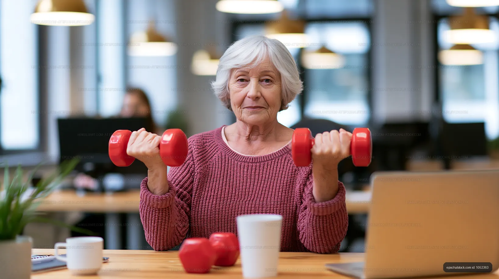 Senior woman exercising with dumbbells in a modern office