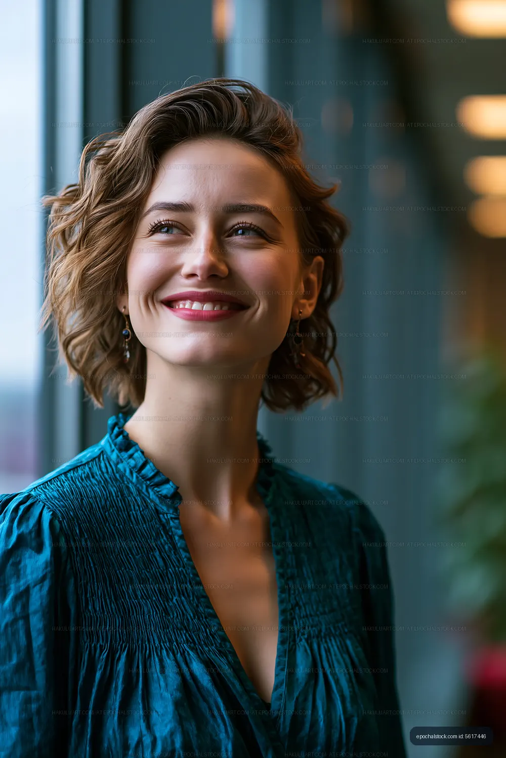 Woman with short hair smiling near a large window indoors