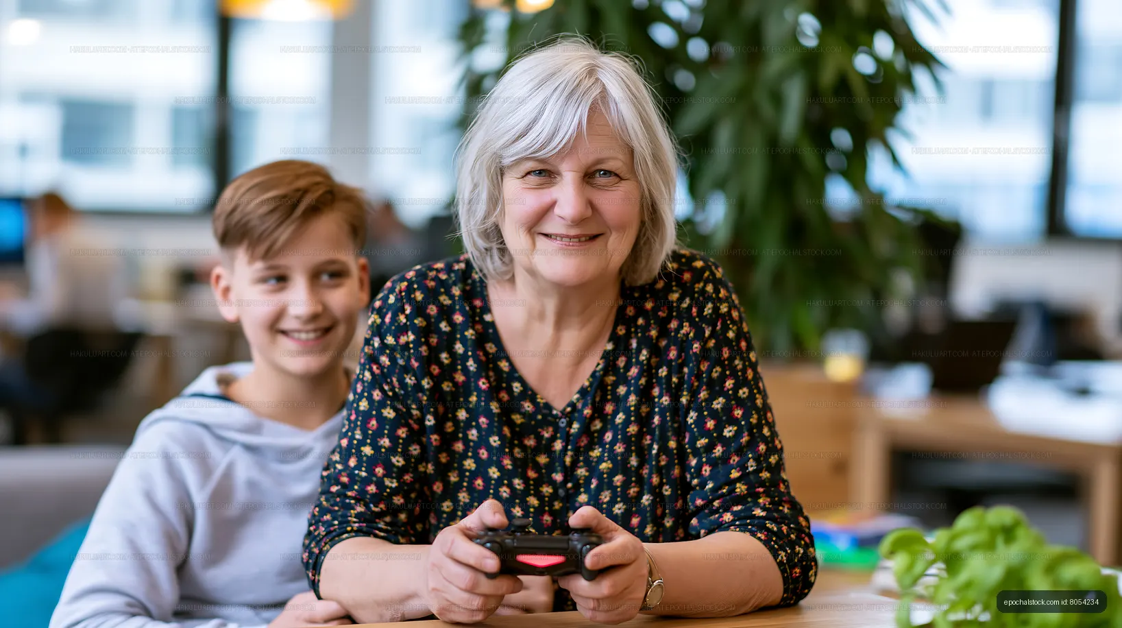 Senior woman and boy playing video games in modern workspace