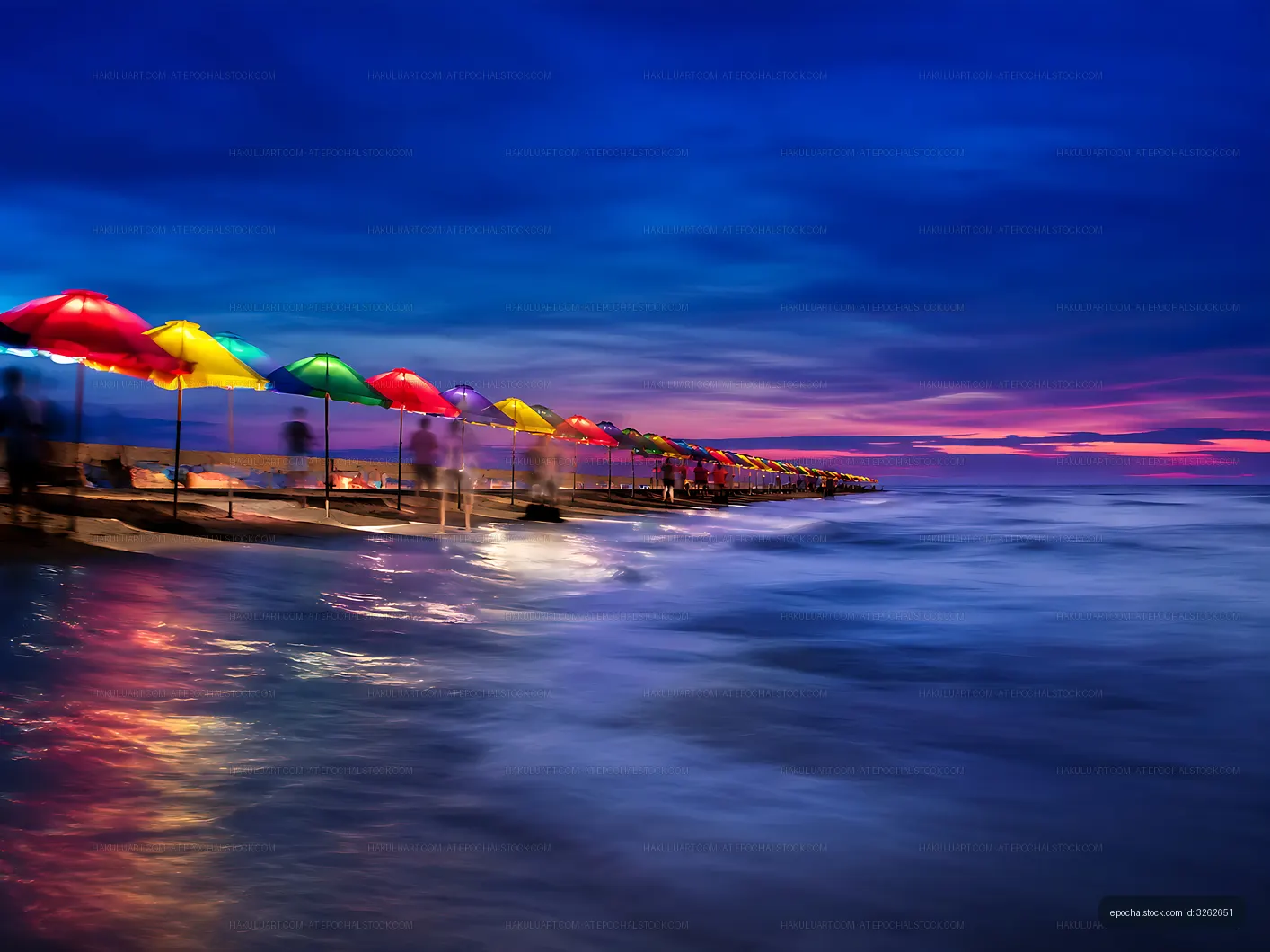 Colorful umbrellas along a pier at sunset by the ocean