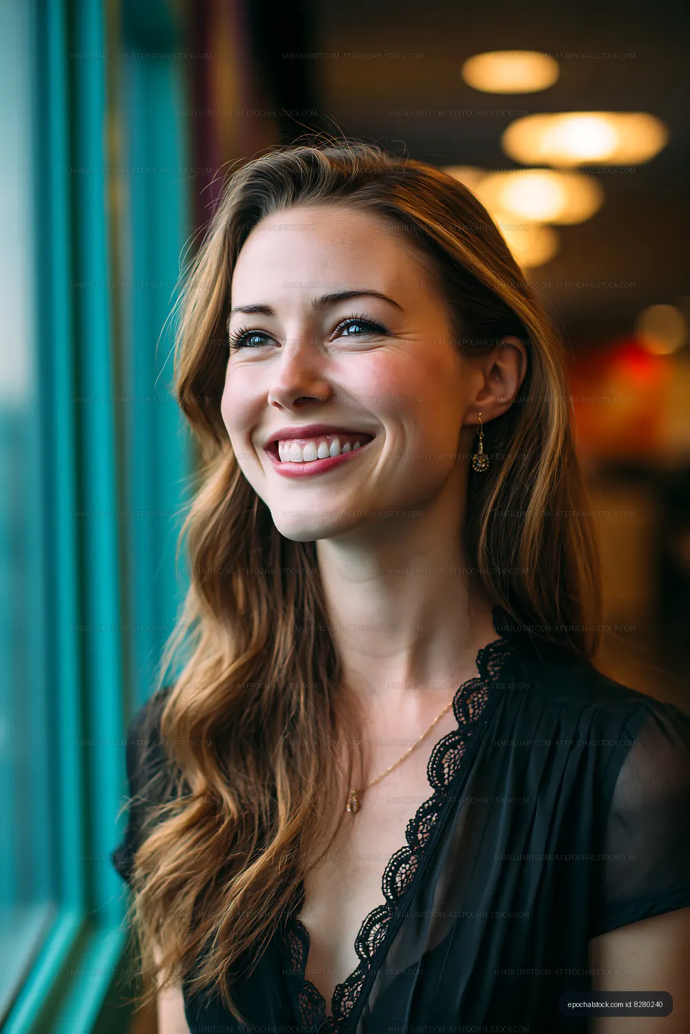 Woman smiling while looking out a window in a softly lit cafe
