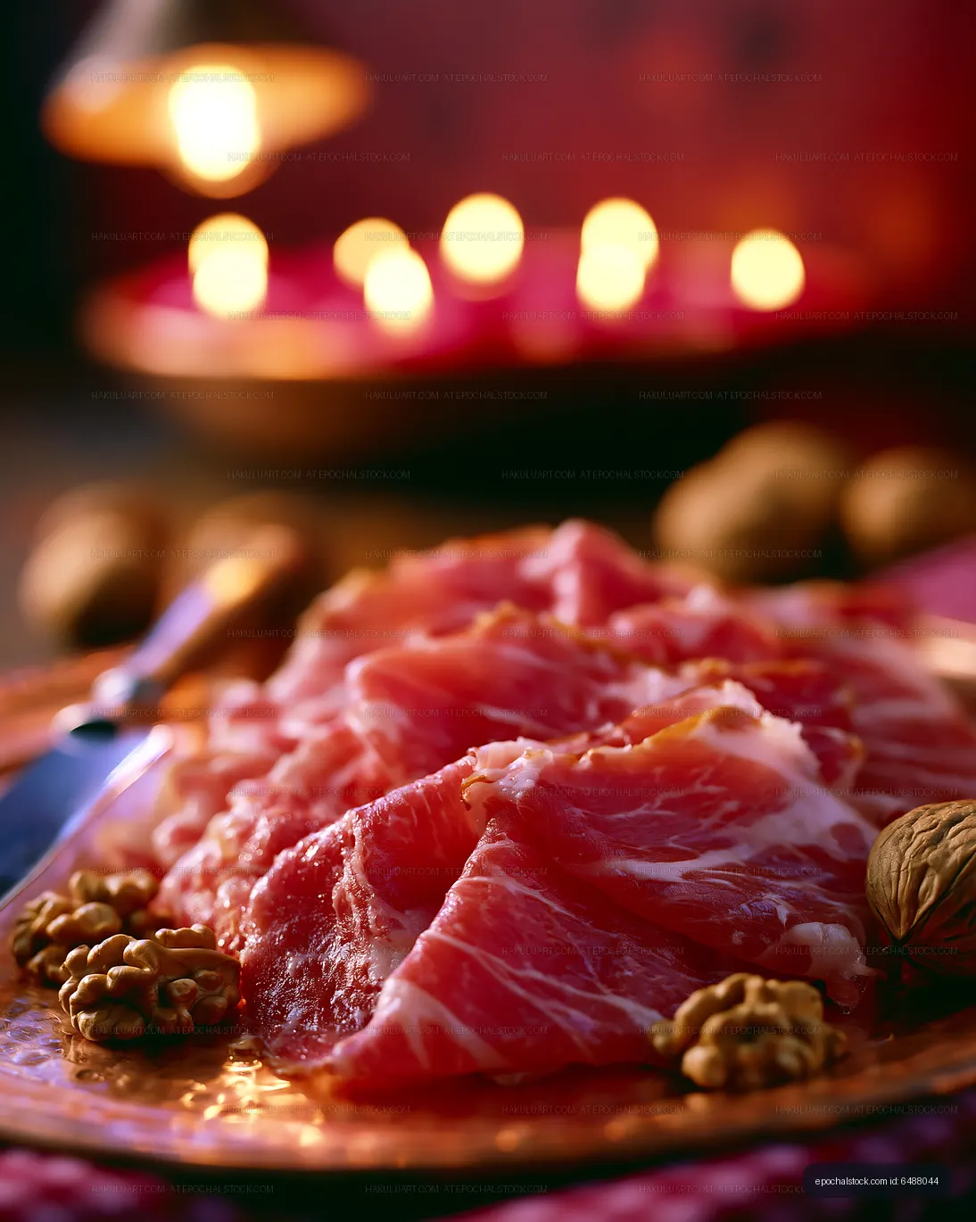 Sliced cured meat on a decorative plate with nuts