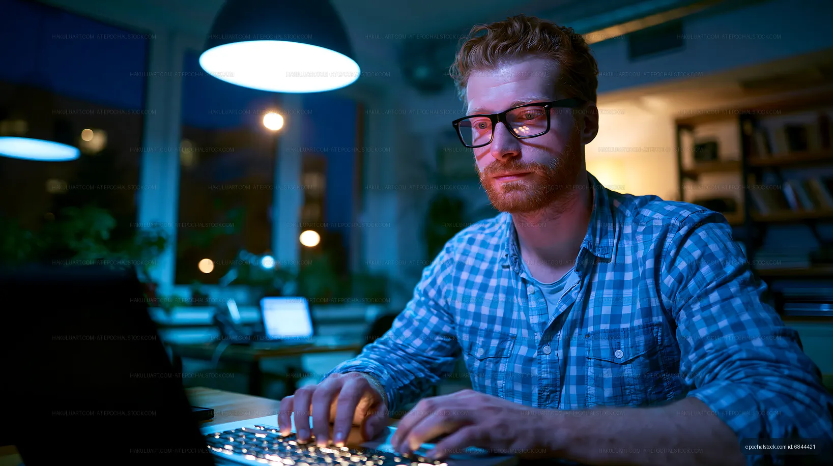 Man working late at night in a bright room with laptop