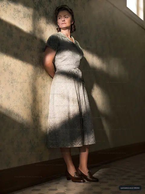 Woman standing against a wall in vintage dress with natural light