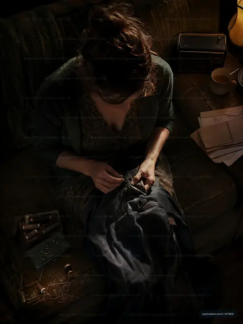 Woman sewing on a couch with thread and tools nearby