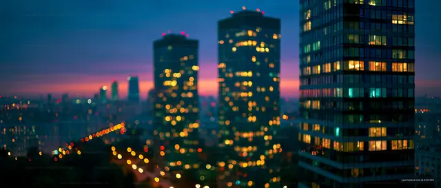 City skyline at dusk with glowing lights and blurred buildings