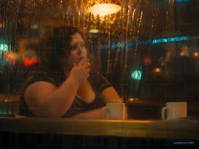 Woman sitting at a cafe table looking out through a rainy window